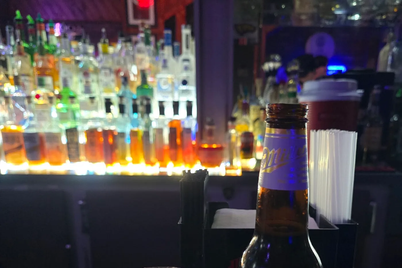 Three tiers of backlit bottles along the back bar at Sugar Bar