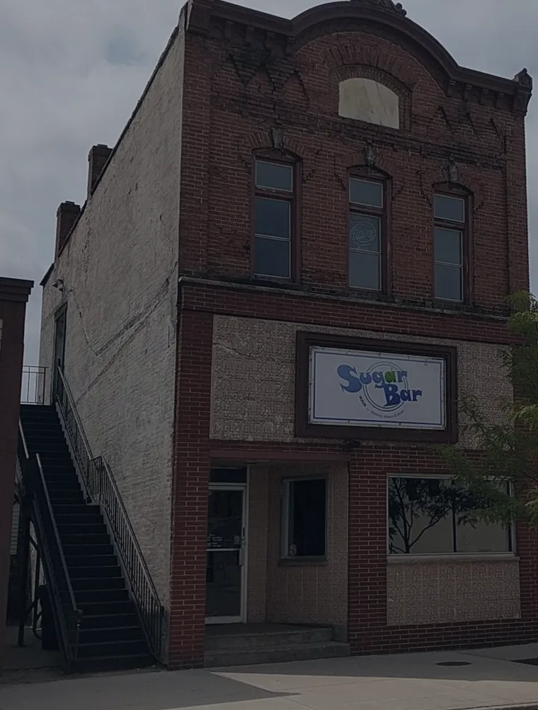 The two-storey red brick storefront at 835 Main St, Stevens Point, with the Sugar Bar sign above the door